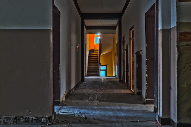 The hallway of an old building with a staircase in the distance