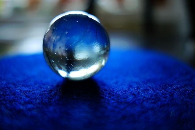 A glass ball sits on a blue tablecloth against a darkened, blurred background